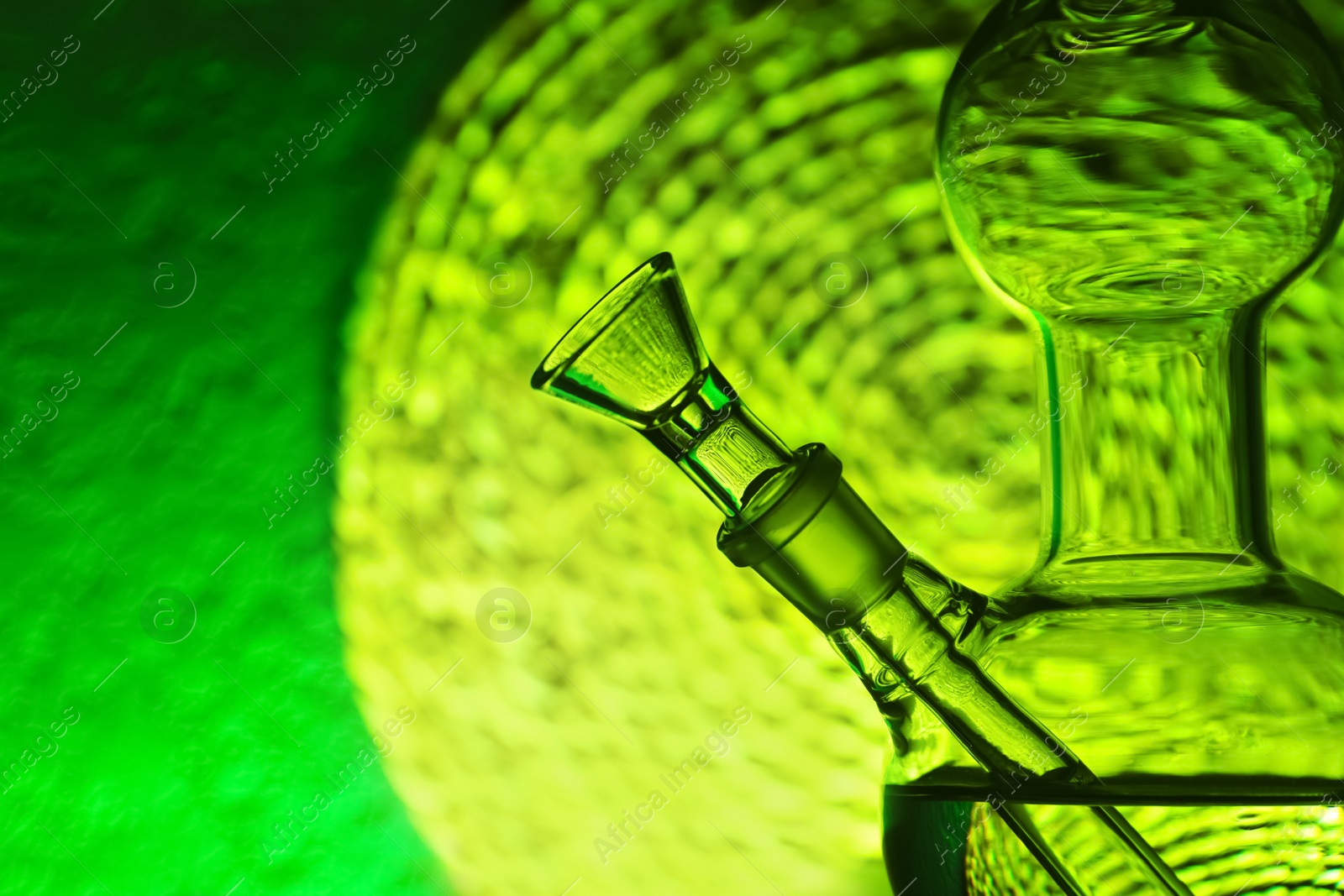 Photo of Closeup view of glass bong on blurred background, space for text. Smoking device