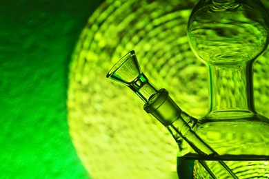 Photo of Closeup view of glass bong on blurred background, space for text. Smoking device