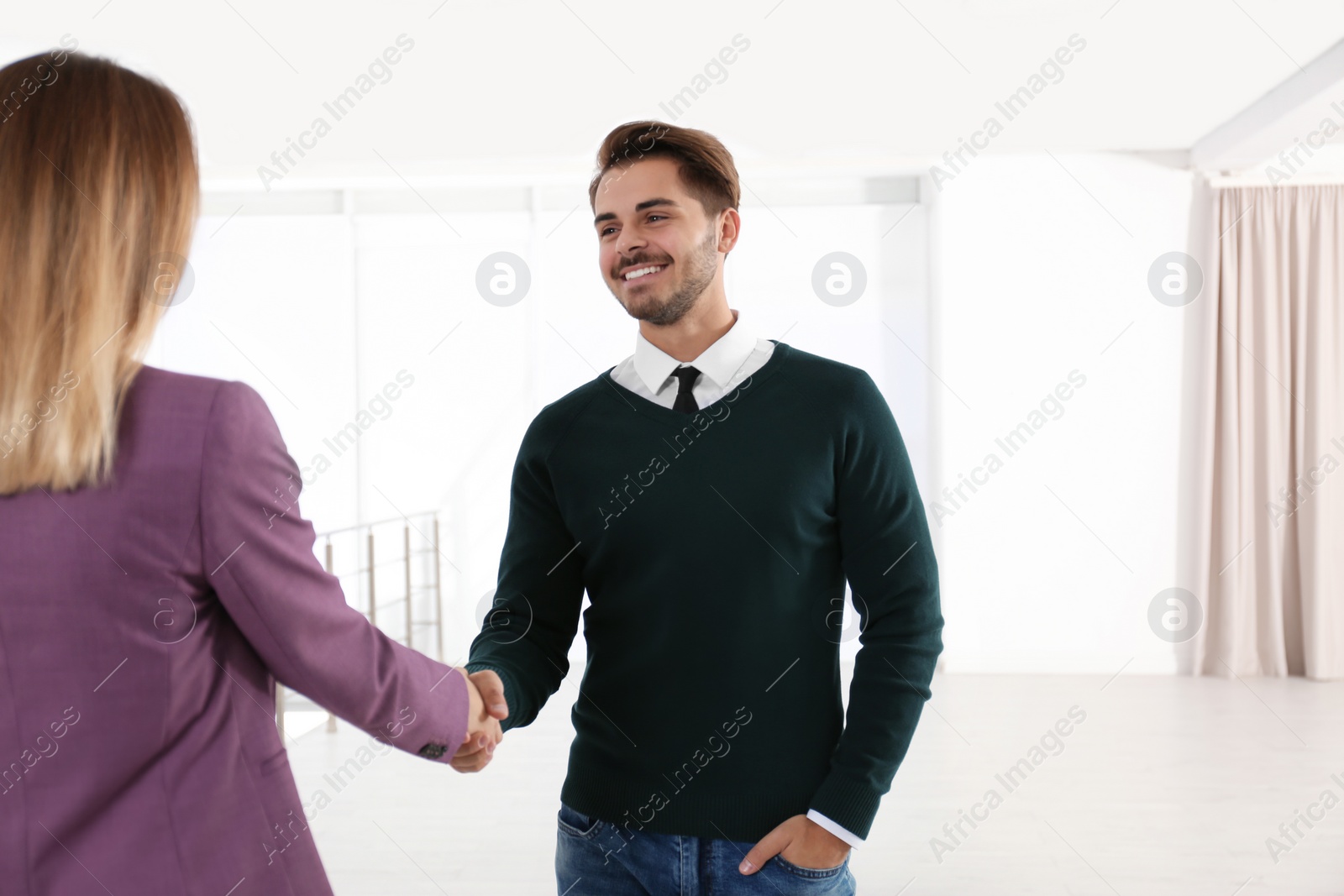 Photo of Real estate agent shaking hands with client in new apartment. Space for text