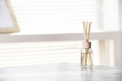 Aromatic reed air freshener on white table at home, space for text