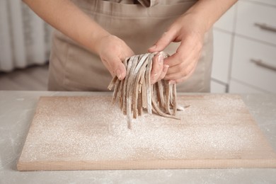 Woman with soba (buckwheat noodles) at light marble table in kitchen, closeup