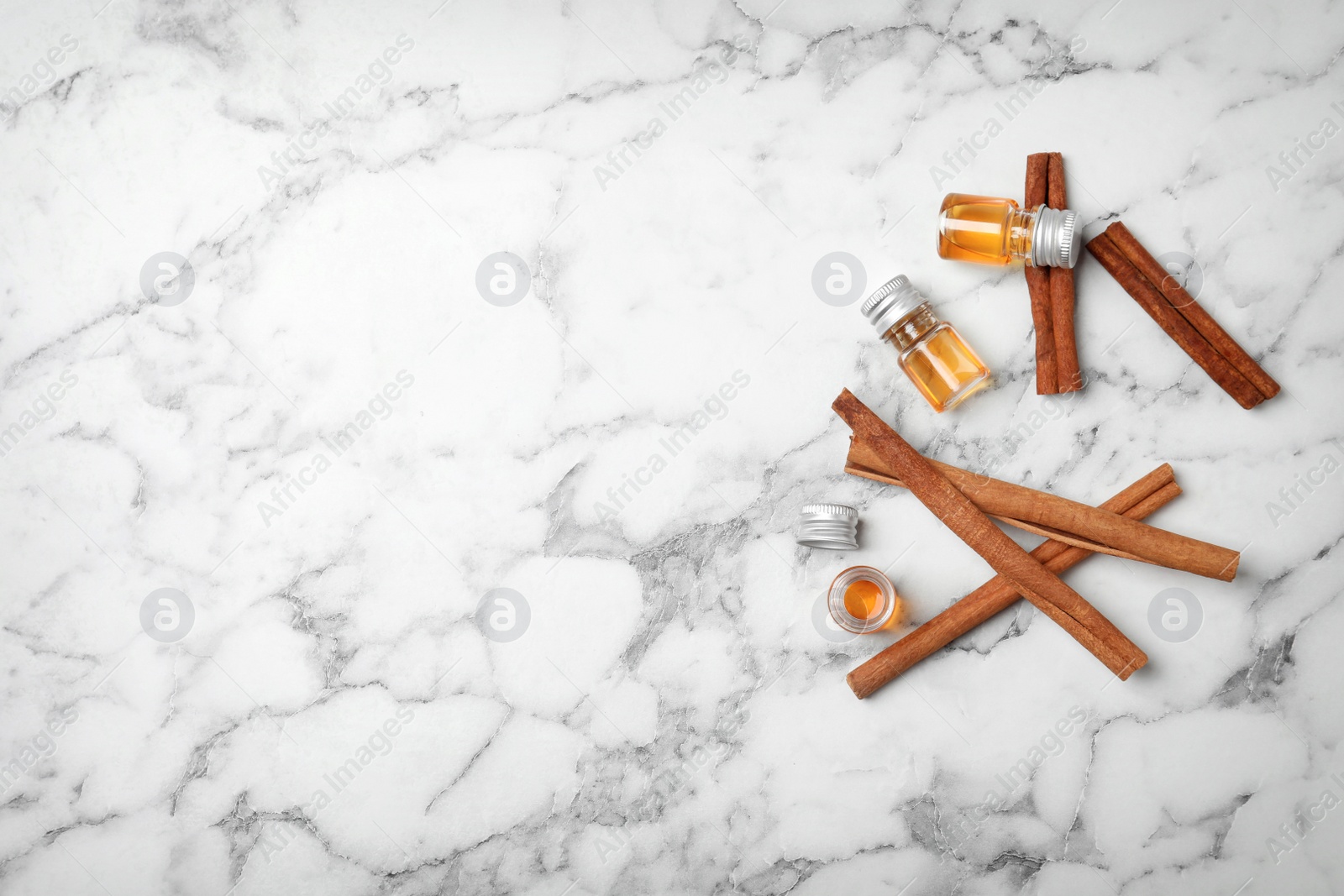 Photo of Bottles with cinnamon oil and sticks on light background