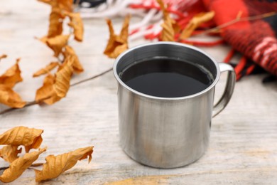 Cup of hot drink and autumn leaves on wooden table