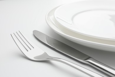 Clean plates, fork and knife on white background, closeup