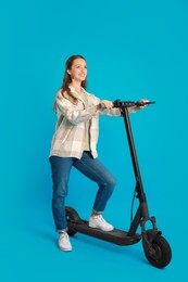 Photo of Happy woman with modern electric kick scooter on light blue background