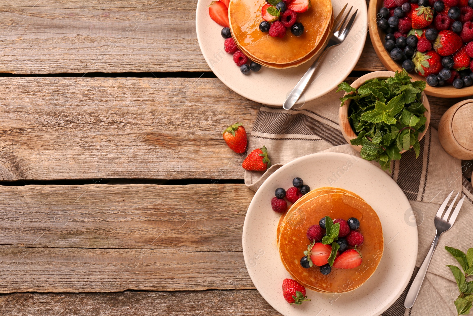 Photo of Tasty pancakes with fresh berries on wooden table, flat lay. Space for text