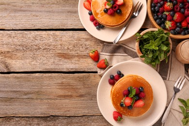 Tasty pancakes with fresh berries on wooden table, flat lay. Space for text