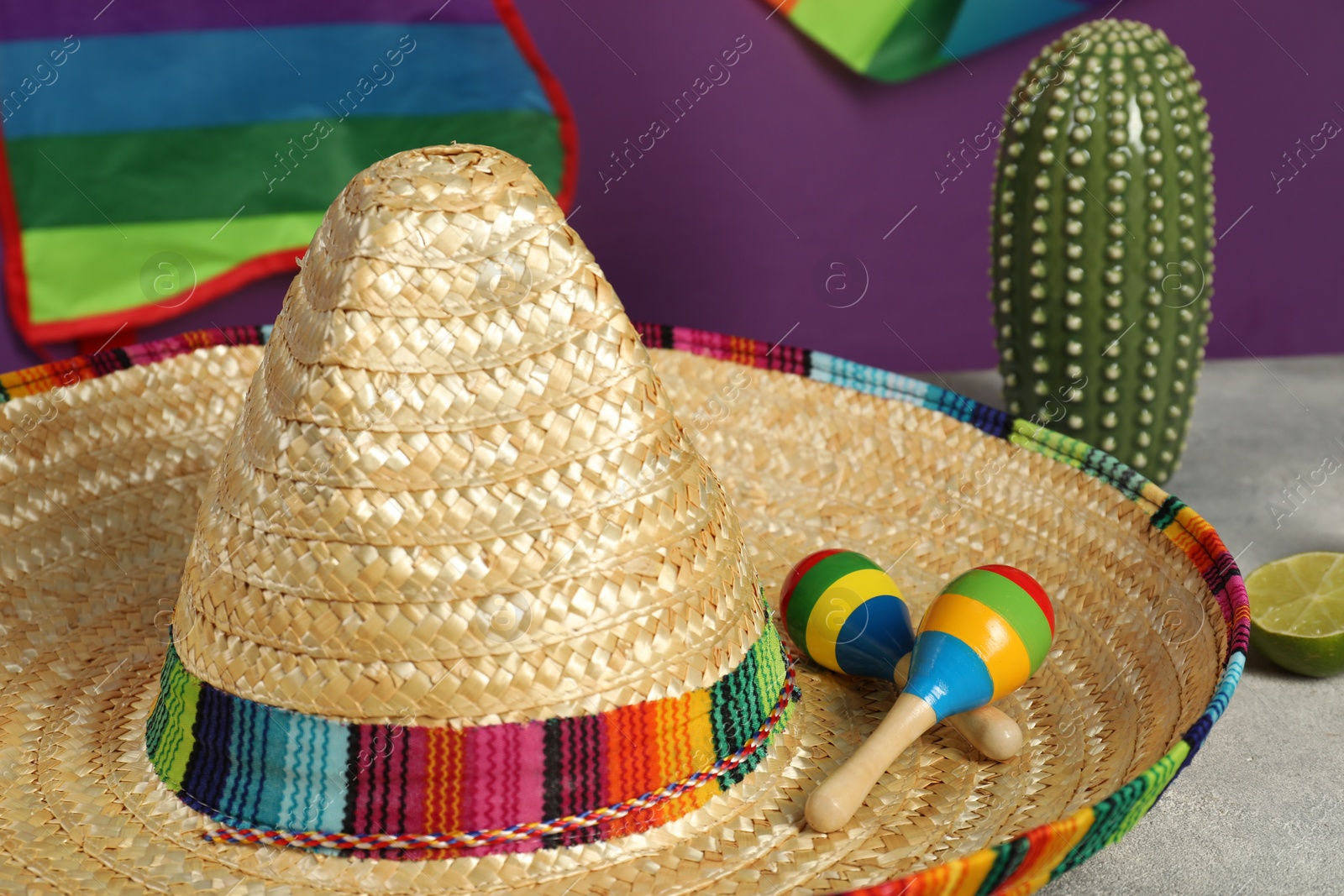 Photo of Mexican sombrero hat and maracas on grey table, closeup