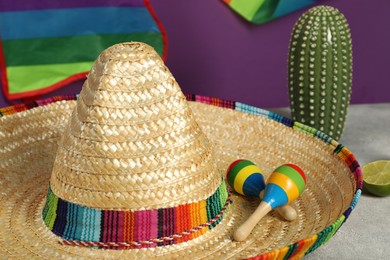 Mexican sombrero hat and maracas on grey table, closeup