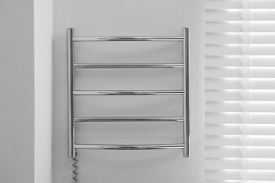 Photo of Heated towel rail on white wall in bathroom