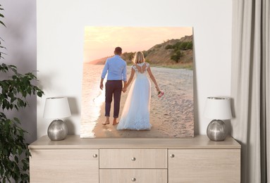 Image of Canvas with printed photo of bride and groom walking at sunset on chest of drawers in room