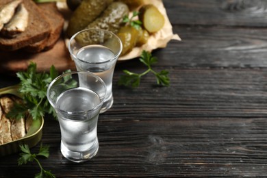 Photo of Cold Russian vodka with snacks on black wooden table