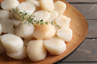 Photo of Fresh raw scallops and thyme on wooden table, closeup