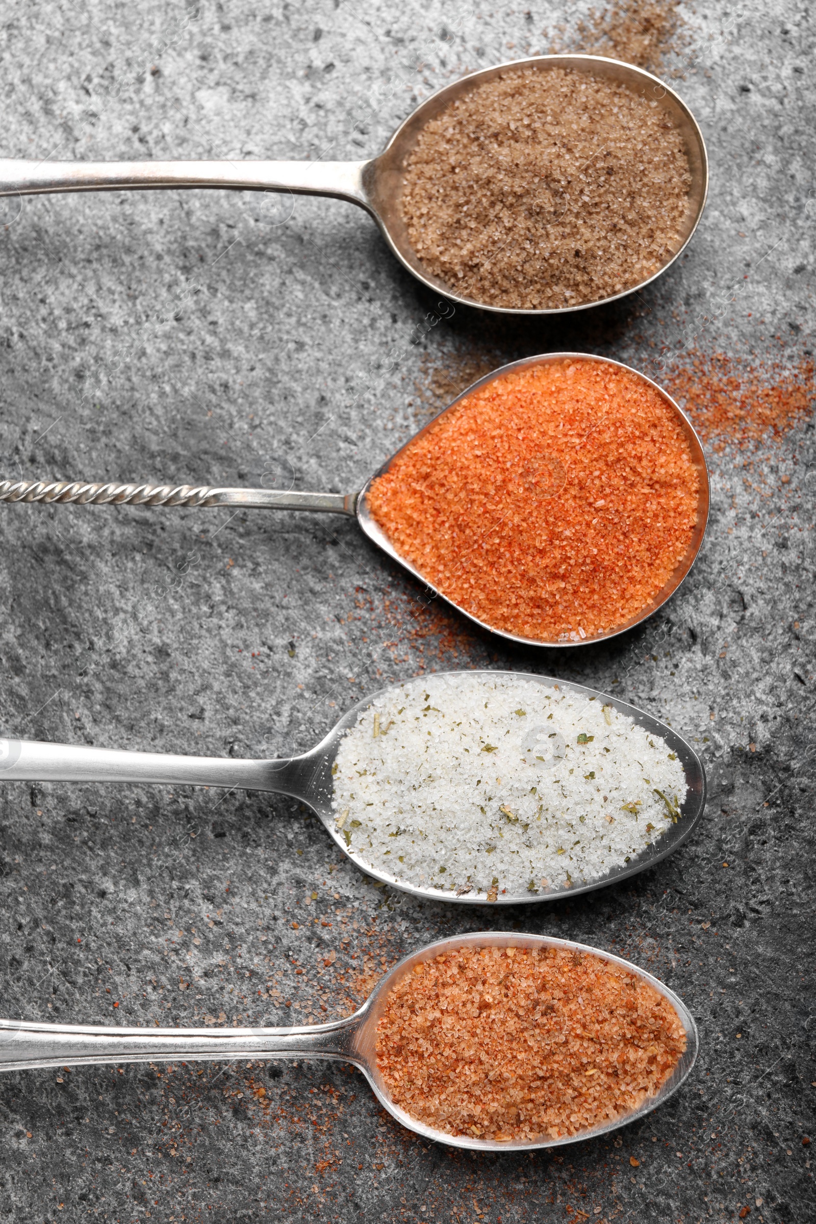 Photo of Different kinds of salt on grey table, flat lay