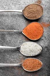 Photo of Different kinds of salt on grey table, flat lay