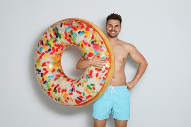Photo of Handsome young man with bright inflatable ring on light background
