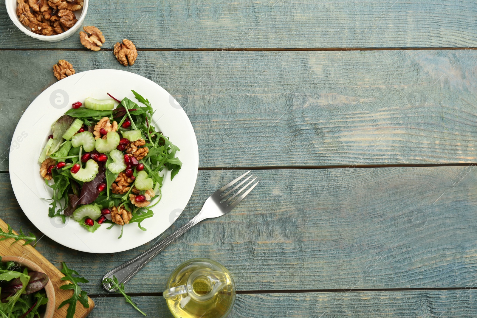 Photo of Delicious fresh celery salad served on light blue wooden table, flat lay. Space for text