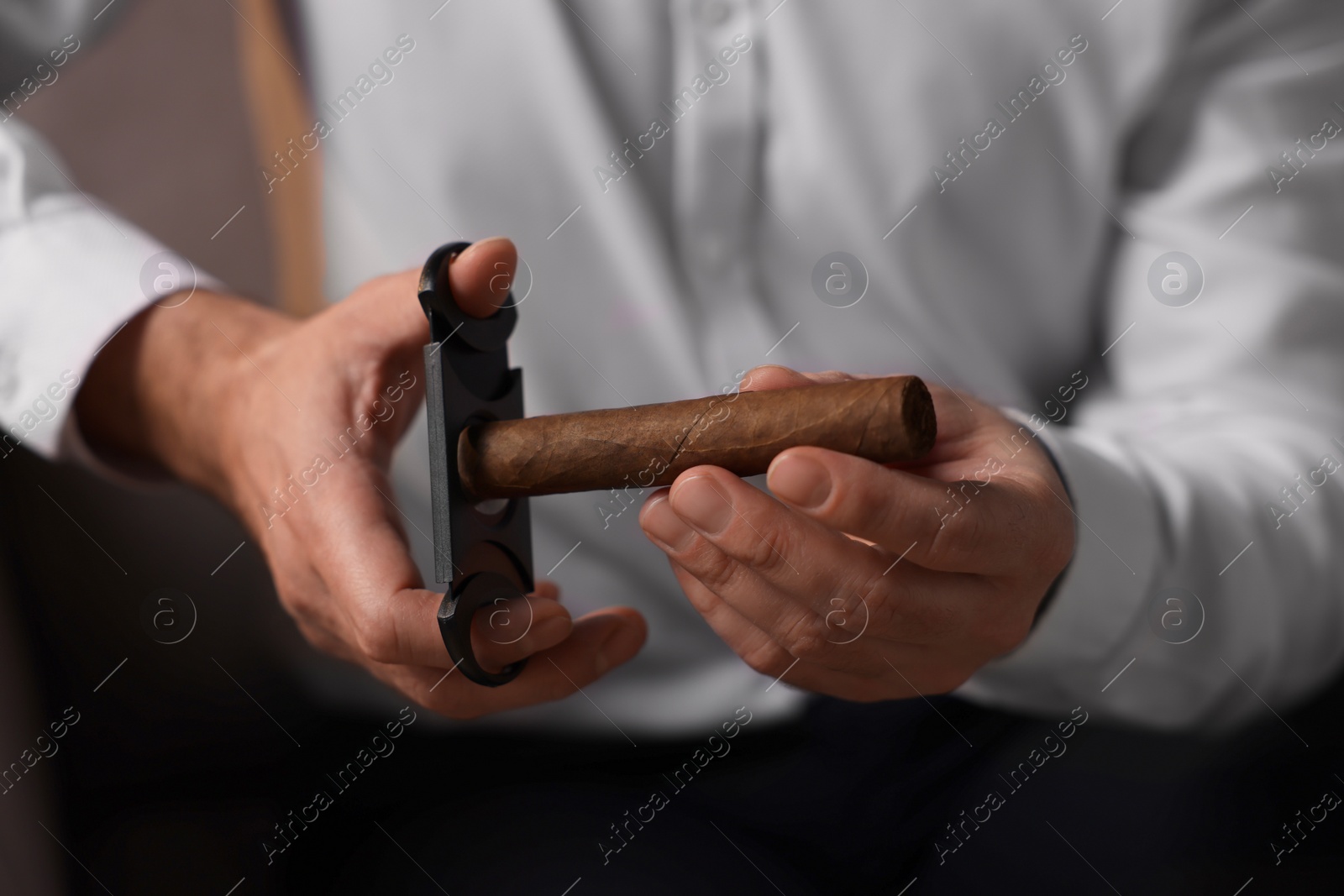 Photo of Man cutting tip of cigar, closeup view