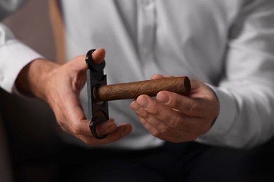 Man cutting tip of cigar, closeup view