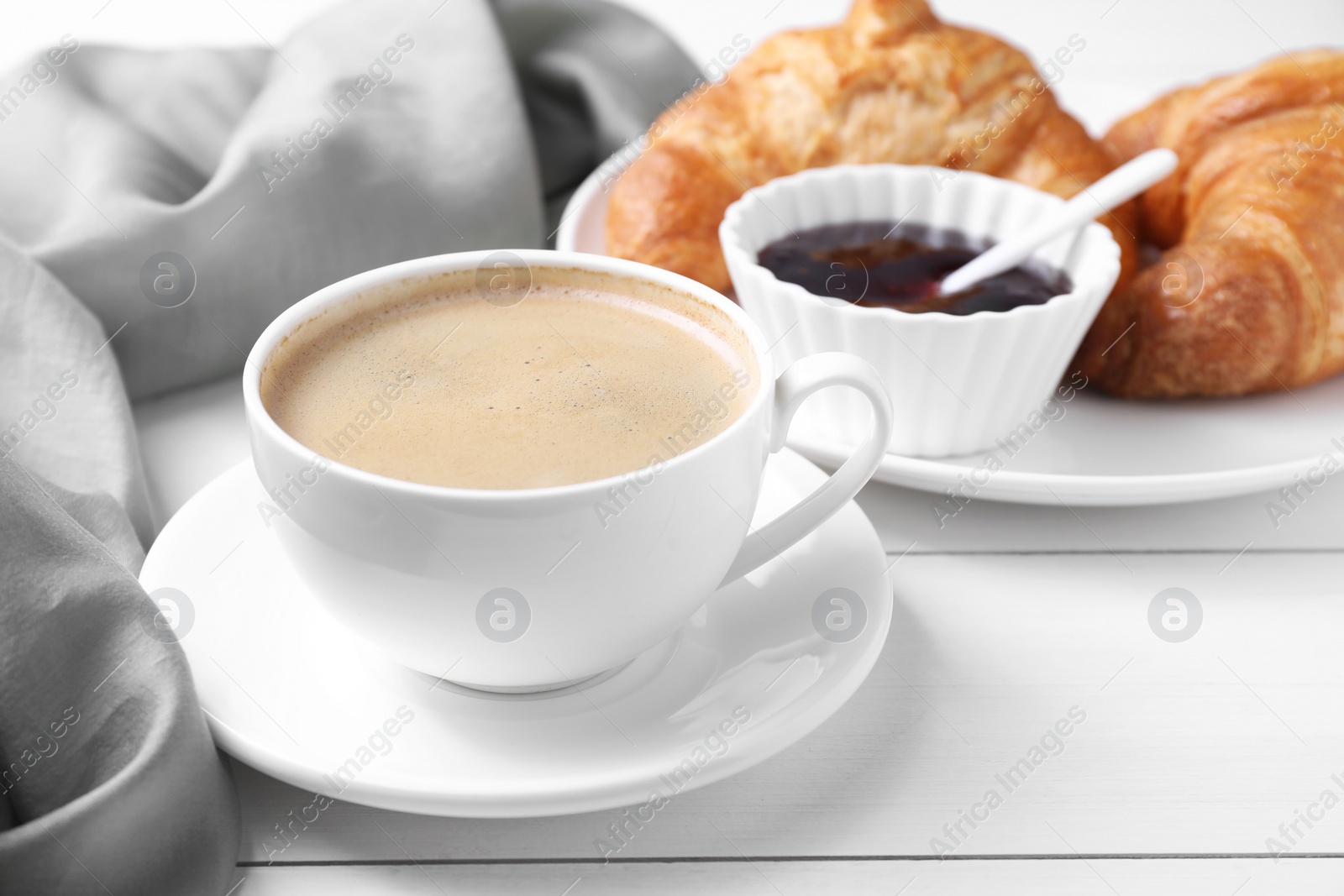 Photo of Fresh croissants, jam and coffee on white wooden table. Tasty breakfast