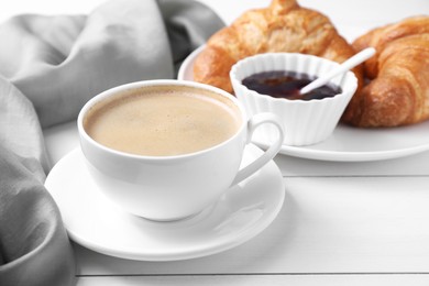 Photo of Fresh croissants, jam and coffee on white wooden table. Tasty breakfast