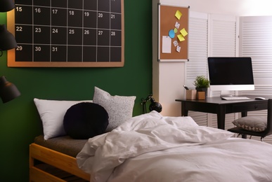 Modern teenager room interior with comfortable bed against green wall