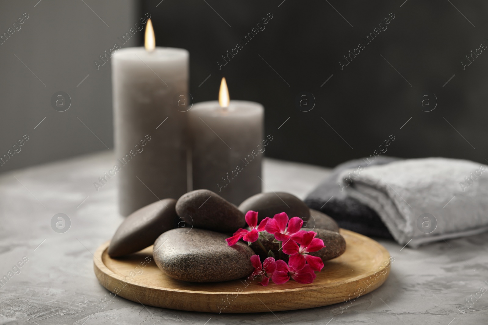 Photo of Spa stones and red flowers on grey table