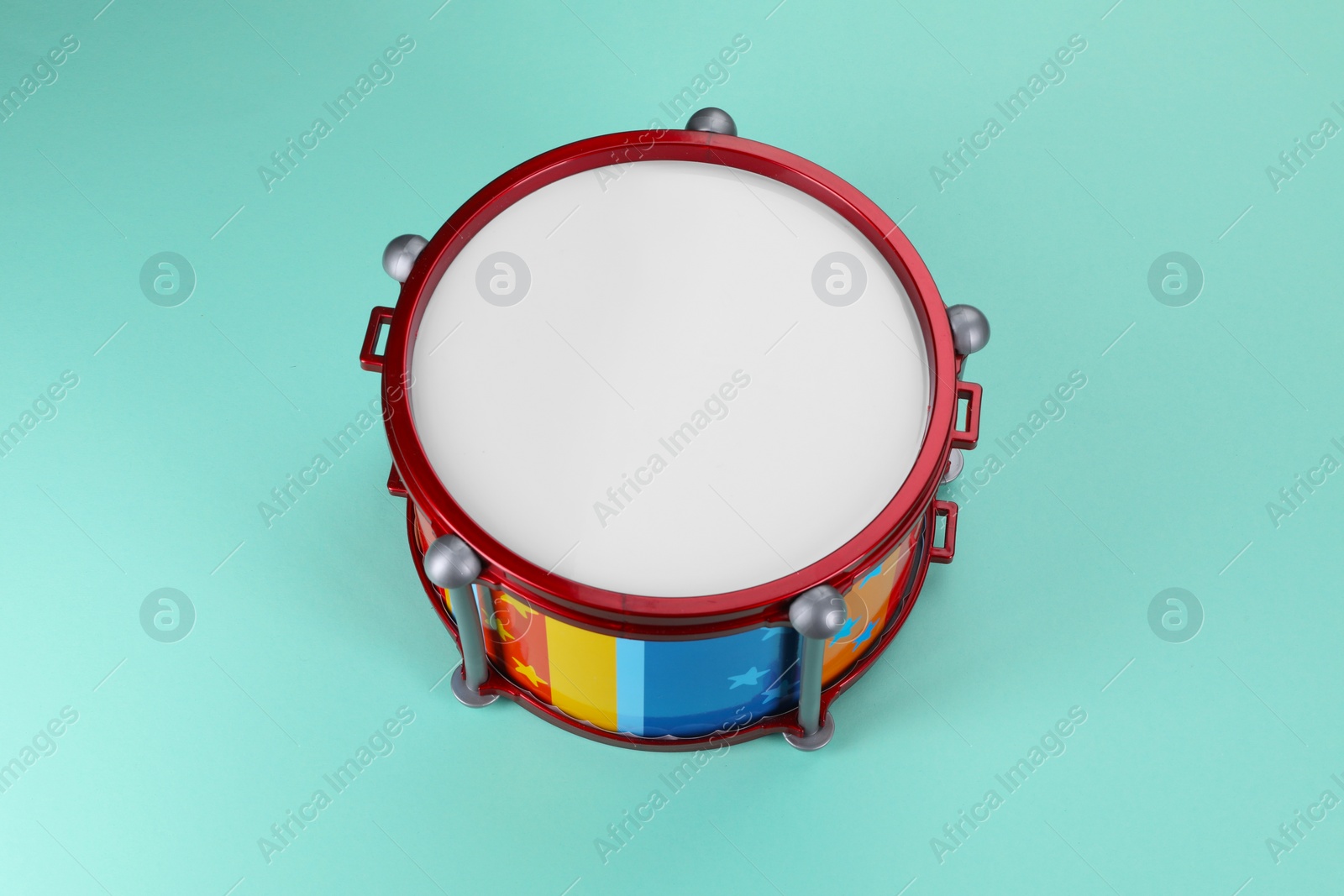 Photo of Children's drum on turquoise background. Percussion musical instrument