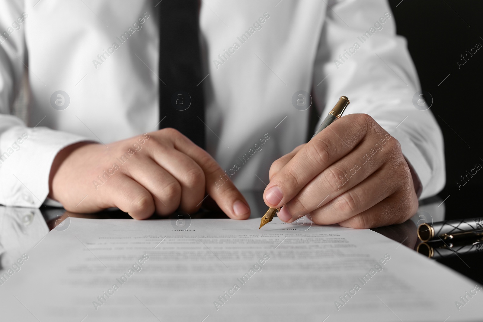 Photo of Notary signing document at black table, closeup