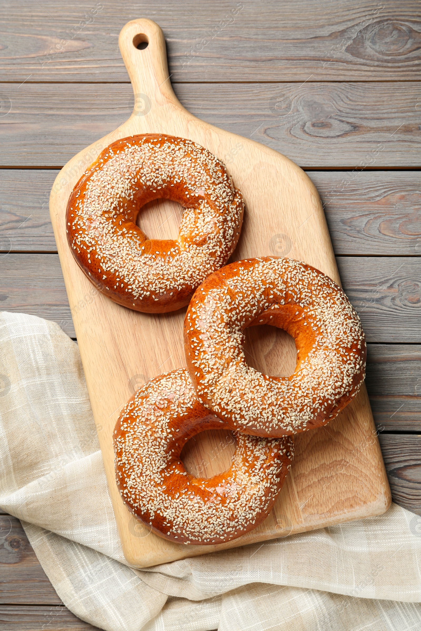 Photo of Delicious fresh bagels with sesame seeds on wooden table, top view