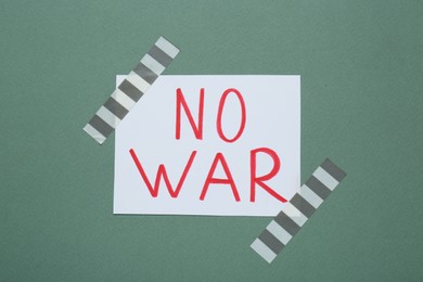 Photo of Phrase No War attached with adhesive tape on green background