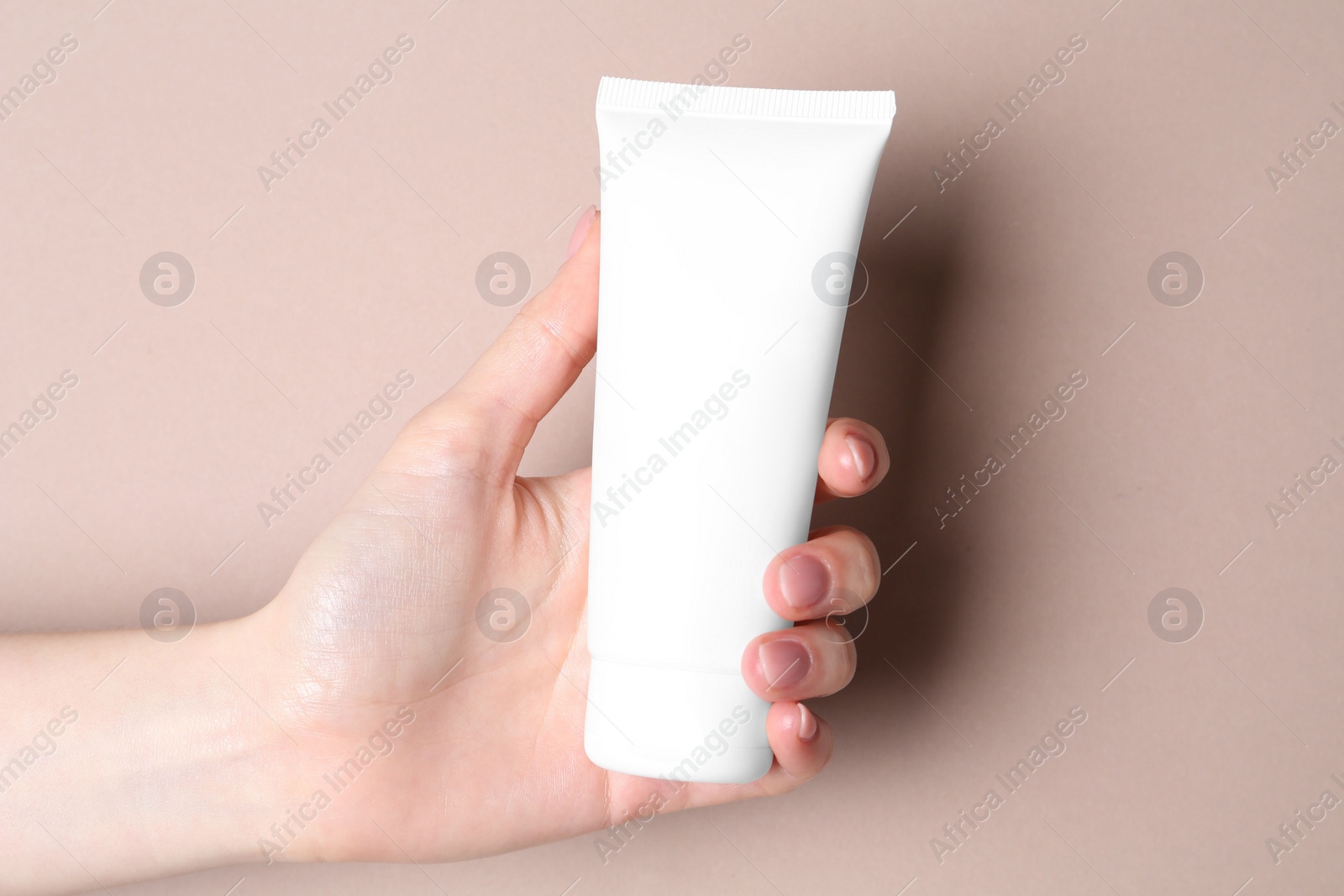 Photo of Woman with tube of cream on beige background, closeup