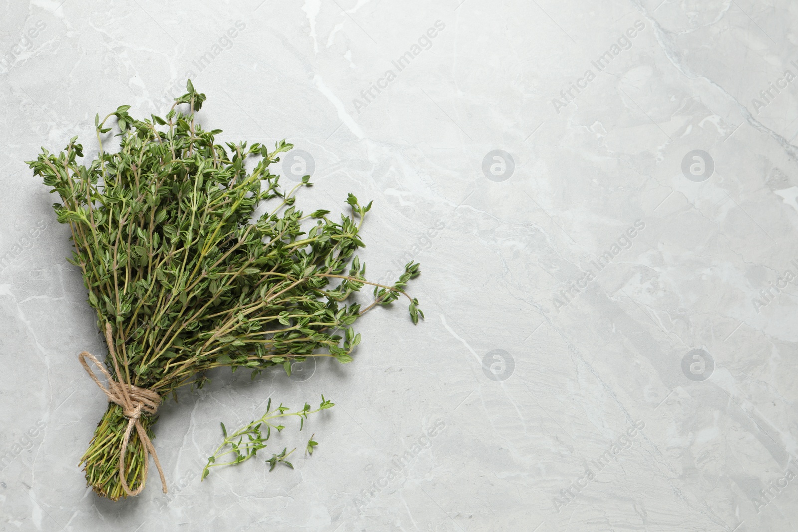 Photo of Bunch of aromatic thyme on light table, top view. Space for text