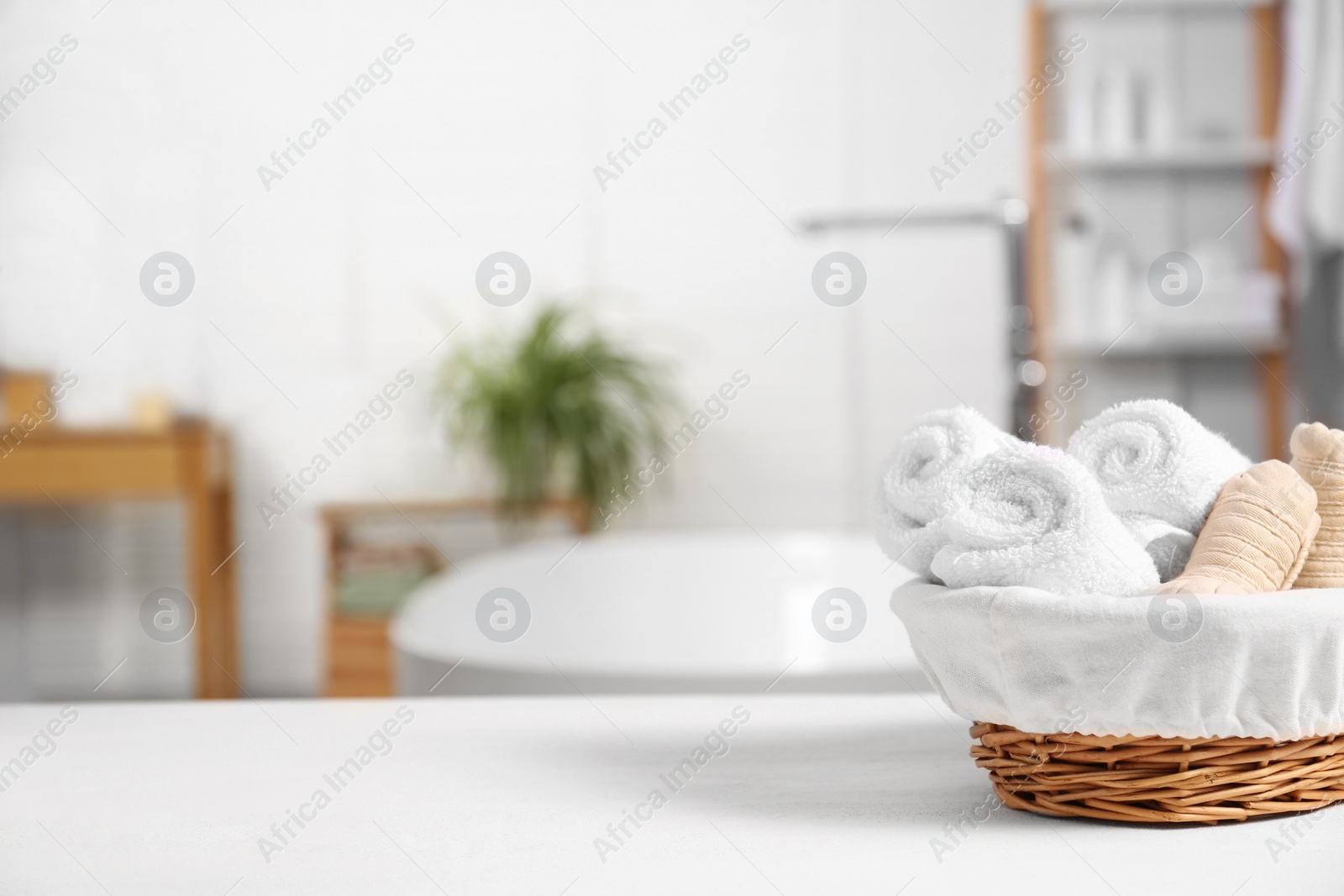 Photo of Basket with spa herbal bags and towels on white table in bathroom, space for text