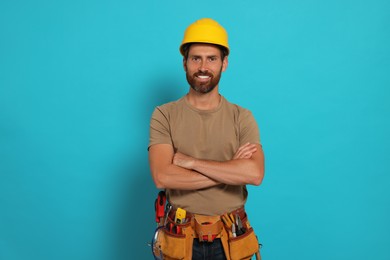 Photo of Professional builder in hard hat with tool belt on light blue background