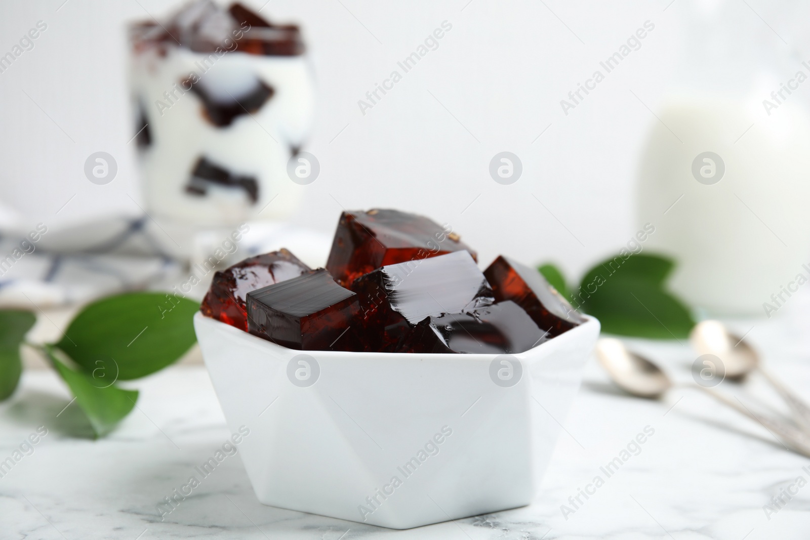 Photo of Delicious grass jelly cubes on white marble table, closeup