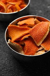 Photo of Bowls with dry orange peels on gray textured table, closeup