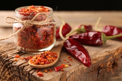 Photo of Chili pepper flakes and pods on wooden table, closeup