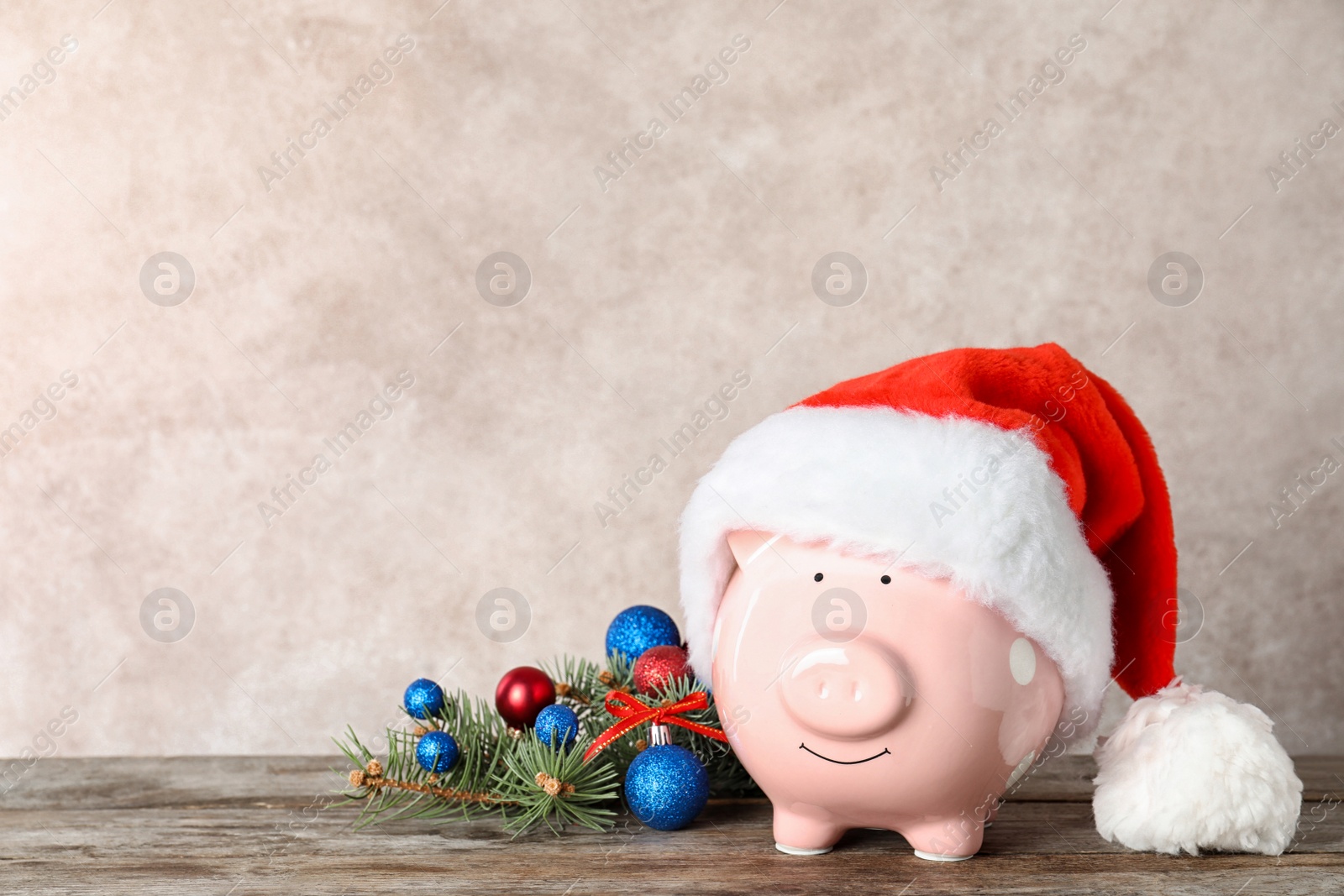 Photo of Composition with piggy bank and Christmas decor on table. Space for text