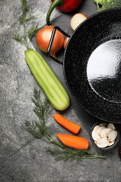 Photo of Empty iron wok and raw ingredients on grey table, flat lay