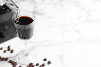 Coffee liqueur and beans on white marble table. Space for text