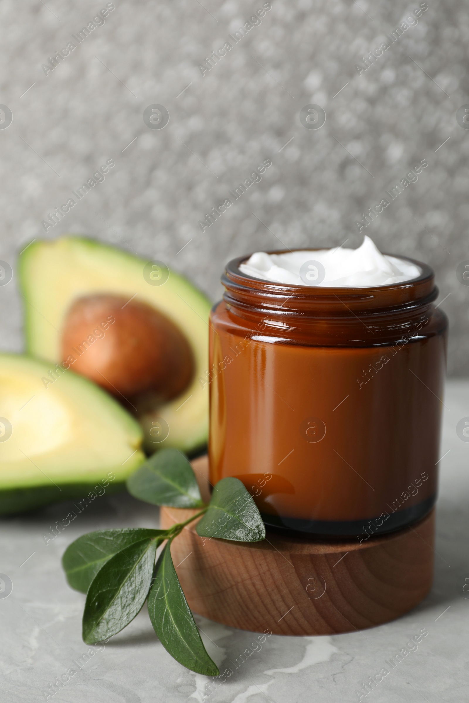 Photo of Jar of face cream and avocado on marble table