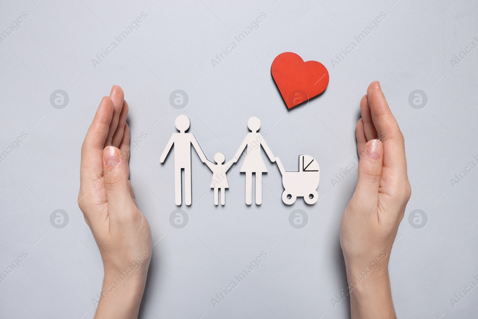 Photo of Woman protecting figures of family and heart on light background, top view. Insurance concept