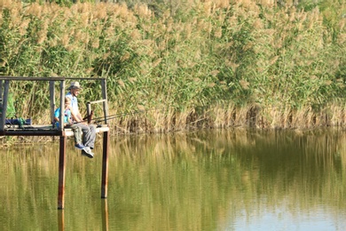 Photo of Father and son fishing together on sunny day. Space for text