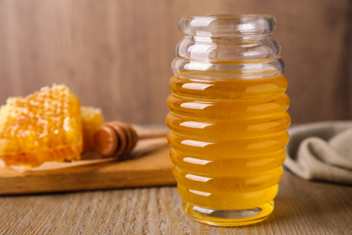 Photo of Jar of tasty aromatic honey on wooden table