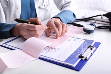 Doctor examining cardiogram at table in clinic, closeup