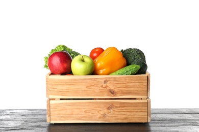 Photo of Wooden crate filled with fresh vegetables and apples on table against white background