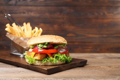 Photo of Delicious tofu burger served with french fries on wooden table. Space for text