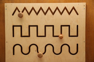 Photo of Wooden sliding maze with different lines on table. Montessori toy