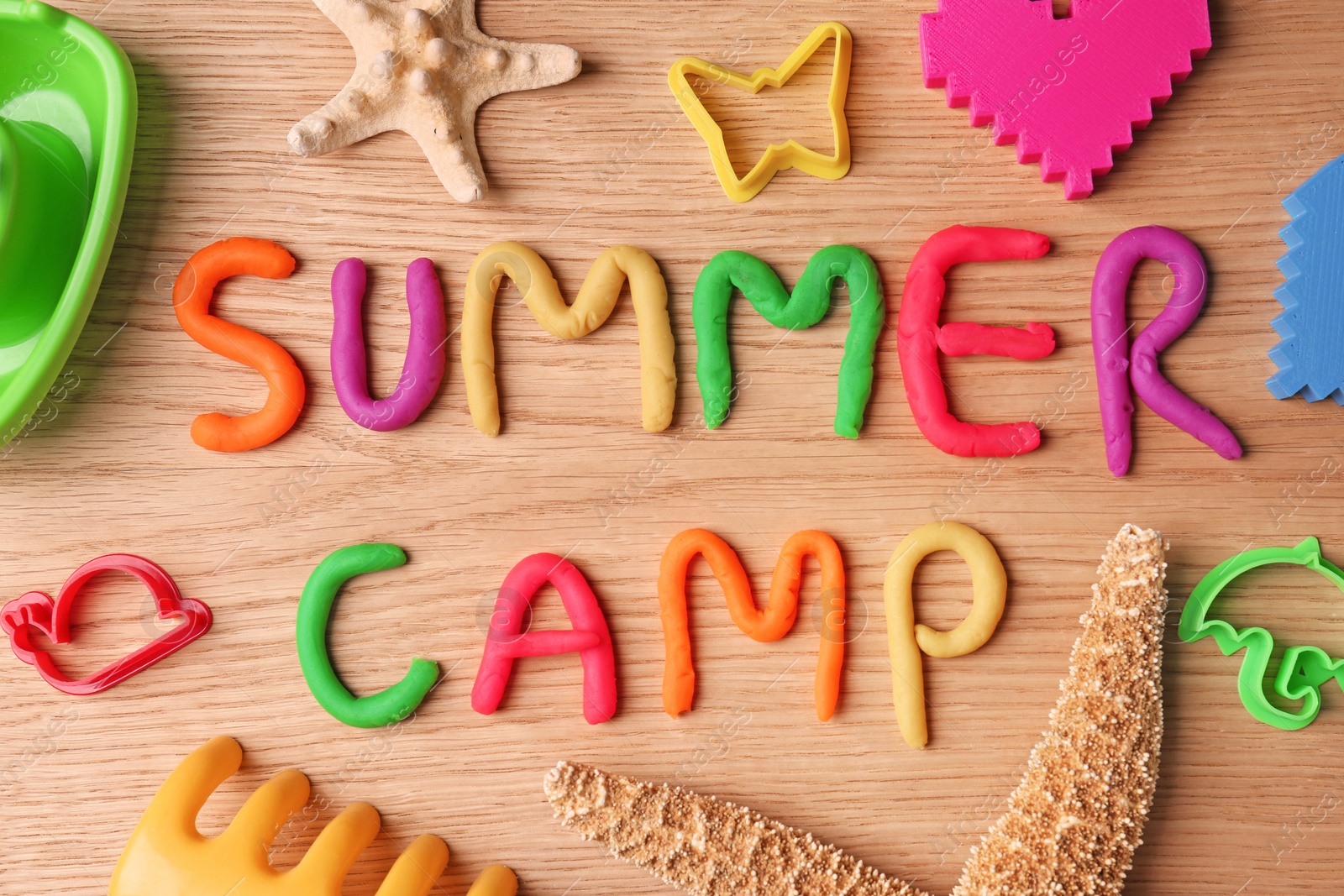 Photo of Text SUMMER CAMP made with play dough on wooden background, top view